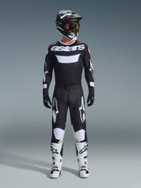 Motocross rider wearing Alpinestars 2026 Racer Air Riway Pants in Black and White, matching black and white jersey with 'astars' logo, black helmet, goggles with iridescent lenses, and white racing boots, complete professional off-road gear set