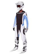 Motocross rider wearing Alpinestars 2025 Techstar Melt Pants, white and black motocross gear with light blue accents, coordinated jersey and gloves, white helmet and goggles, white and black racing boots, professional off-road kit.