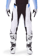 Alpinestars 2025 Techstar Melt Pants, Motocross Pants, White and Black with Light Blue accents, worn with matching white and black boots and gloves, featuring laser-cut perforations and high-performance racing design.