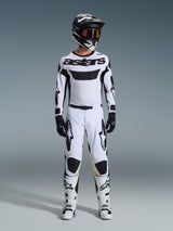 Motocross rider wearing Alpinestars 2026 Racer Riway Pants in White and Black, styled with a matching white jersey, black helmet with red goggles, black gloves, and white boots, featuring bold black Astars branding and a performance-driven design for off-road use.