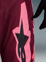 Alpinestars 2026 Racer Riway Pants, Motocross Pants, Dark Red Coral, close-up view showing a large coral pink angular graphic and black star logo, highlighting the durable polyfabric texture and performance stitching