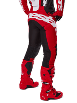 Alpinestars 2025 Racer Veil Pants, Motocross Pants, Black and Bright Red, rear view featuring large white Alpinestars branding across the seat, black stretch panels on back legs, worn with matching red racing boots, durable off-road racing gear