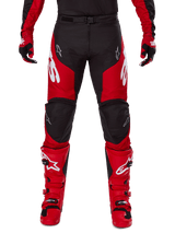 Alpinestars 2025 Racer Veil Pants, Motocross Pants, Black and Bright Red, worn with matching red gloves and boots, featuring large white Alpinestars logos on the thighs, black knee panels, and an adjustable waist buckle for off-road riding