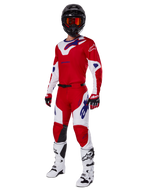 Alpinestars 2025 Racer Veil Pants, Motocross Pants, Bright Red and White, worn as part of a complete racing gear set including a matching red and white jersey, black helmet with orange goggles, white boots, and red gloves, featuring bold blue Alpinestars logos.