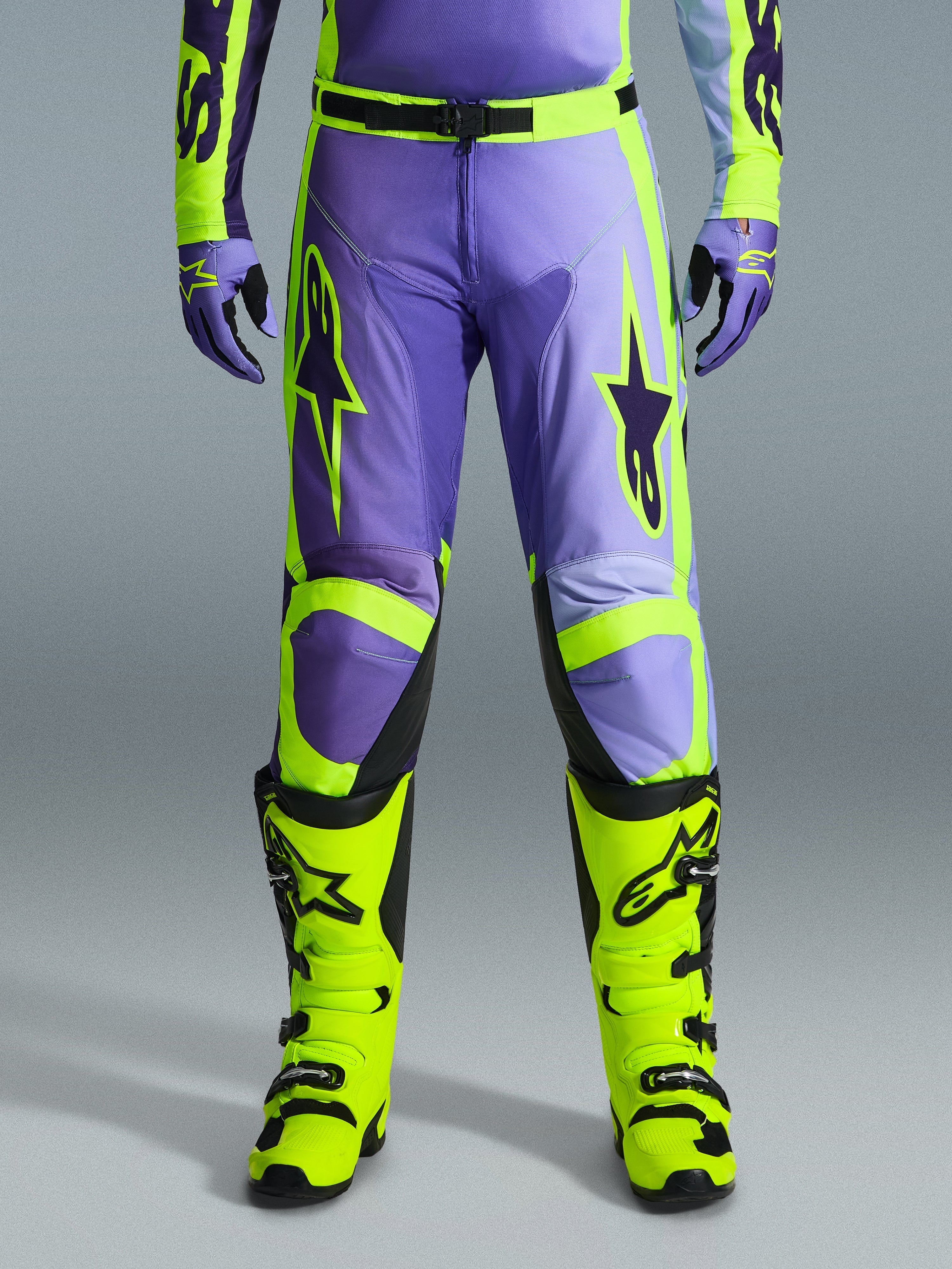 Alpinestars 2026 Racer Portl Pants, Motocross Pants, Purple and Yellow Fluo, worn with matching fluo yellow boots and purple gloves, featuring large star logos and durable polyfabric construction for off-road racing