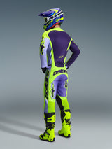 Motocross rider from behind wearing the Alpinestars 2026 Racer Portl Pants in Purple Yellow Fluo, styled with a matching purple and yellow jersey, helmet, and bright yellow racing boots, featuring bold 'astars' branding on the seat and star logos on the legs.