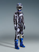 Motocross rider wearing full gear featuring Alpinestars 2026 Racer Lahnd Pants, Iron Camo and gray pattern, matching jersey, bright blue and purple motocross boots, blue and white helmet, professional off-road racing outfit