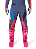 Alpinestars 2025 Techstar Dreem Pants, Motocross Pants, Gray Multicolor with blue, pink, and orange accents, worn with bright pink boots and white and black gloves, featuring laser-cut perforations on the thighs and a magnetic waist buckle, athletic race-fit gear for off-road competition