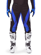 Alpinestars 2025 Techstar Dreem Pants, Motocross Pants, Black and Blue, worn with matching jersey, gloves and white boots, featuring blue side panels and athletic race fit, durable material for off-road racing