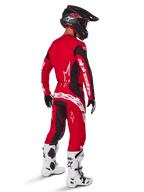 Alpinestars 2025 Techstar Dreem Pants, Motocross Pants, Bright Red and Black, worn by a rider from a rear perspective in a full racing kit with matching red jersey, black helmet, and white boots, featuring bold white Alpinestars branding and black stretch panels.