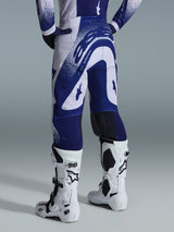 Alpinestars 2026 Supertech Scenz Pants, Motocross Pants, Light Gray and Dark Blue, rear view worn with matching jersey and white boots, featuring bold blue graphics with speckled accents, performance athletic fit for off-road racing.