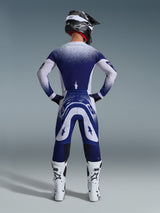 Alpinestars 2026 Supertech Scenz Pants, Motocross Pants, Light Gray and Dark Blue, rear view of a rider wearing a matching gear set with speckled gradient graphics, white boots and black helmet, professional athletic fit for off-road racing