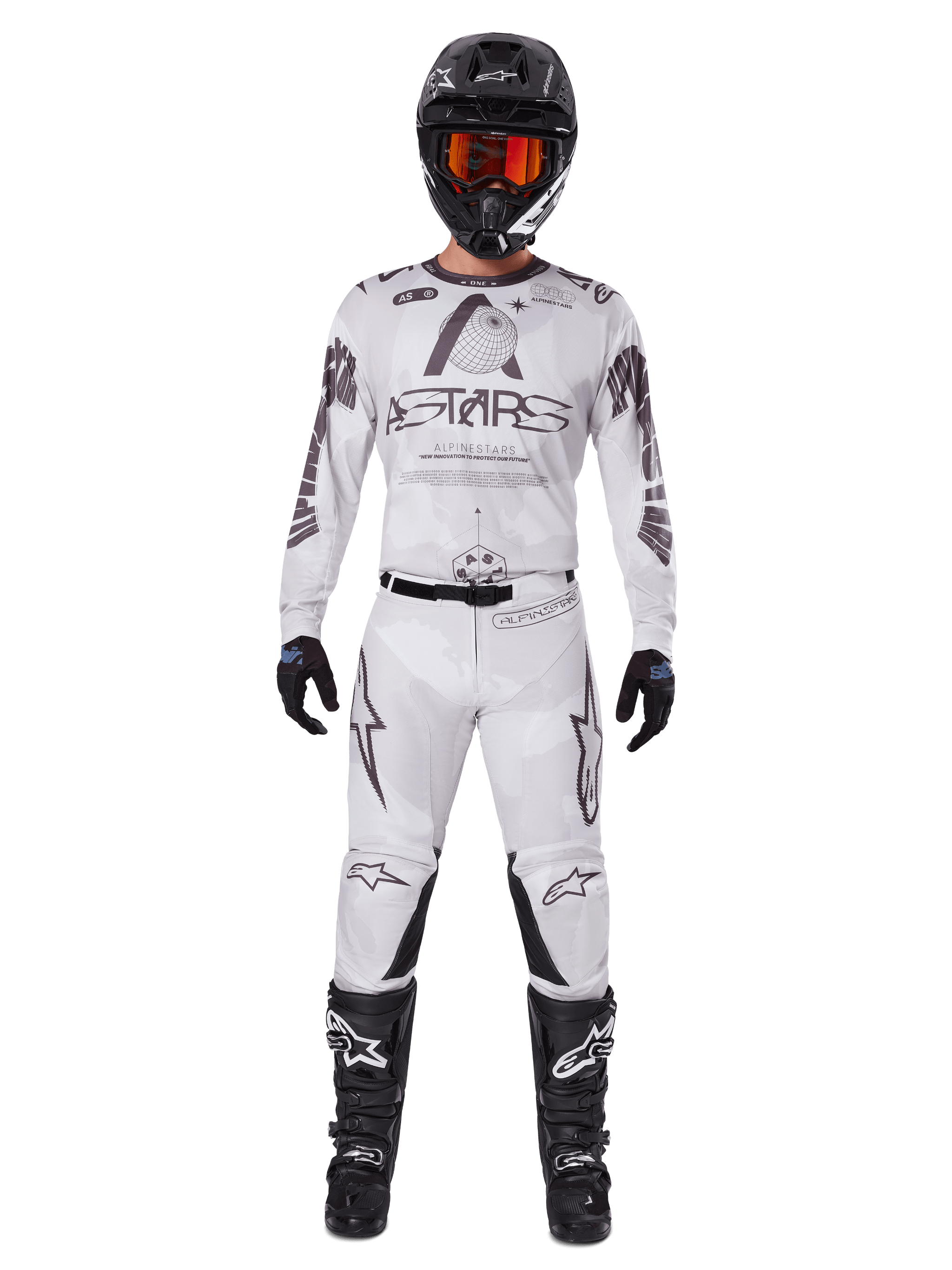 Motocross rider wearing the Alpinestars 2025 Racer Hollow Pants in Light Camo Brown, paired with a matching white and grey long-sleeve jersey, black helmet with orange-red goggles, black gloves, and black boots, coordinated racing gear set for off-road performance.
