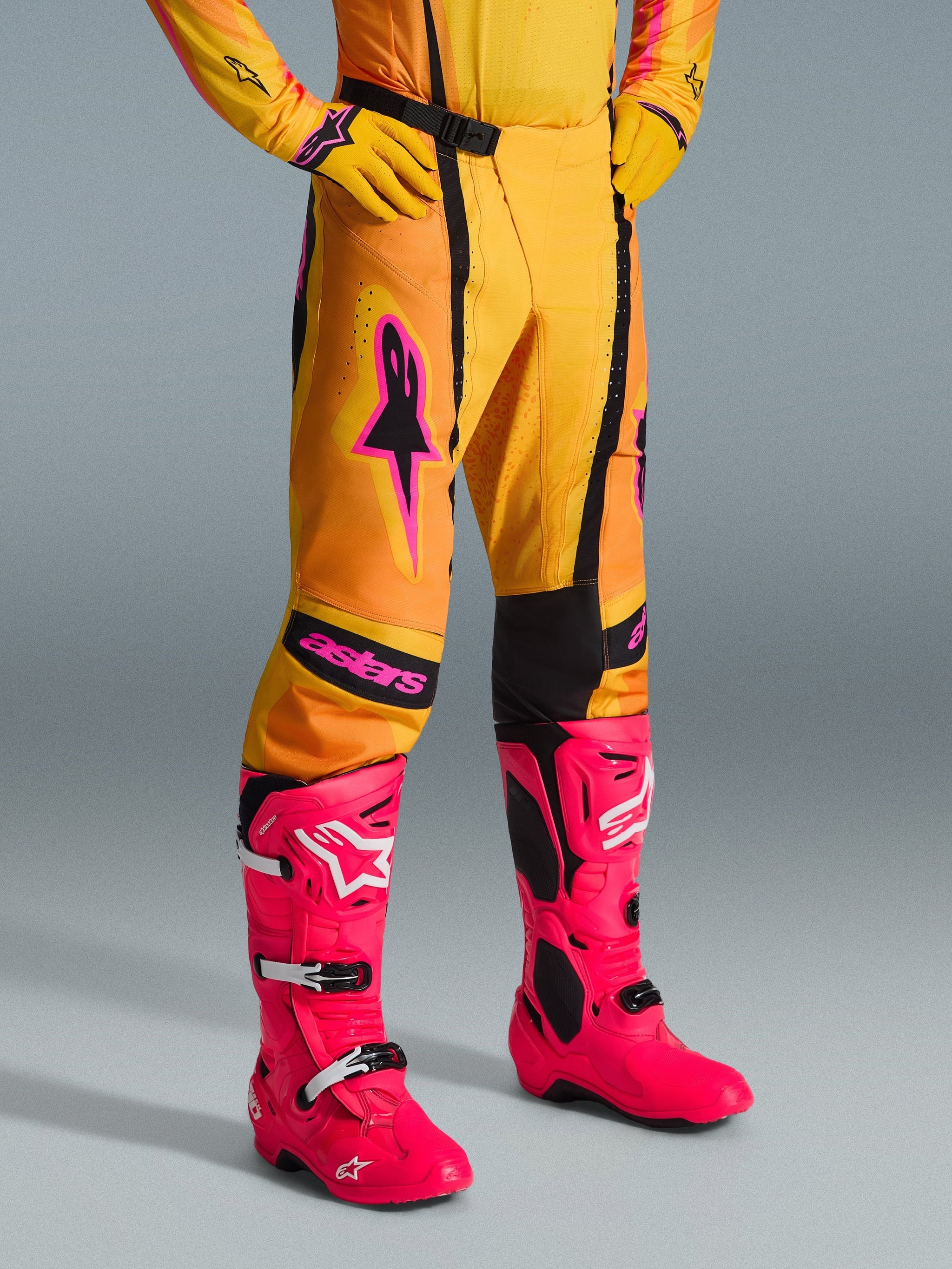 Alpinestars 2026 Techstar Nomur Pants, Motocross Pants, Orange Yellow and Pink, worn with matching yellow jersey and gloves and bright pink boots, athletic race fit with pink branding and black magnetic buckle, vibrant gear for off-road competition