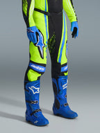 Alpinestars 2026 Techstar Nomur Pants, Motocross Pants, Yellow Fluo, Dark Navy, and UCLA Blue, worn with matching blue boots and gloves, featuring bold white logos and reinforced panels, professional off-road racing attire