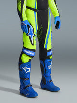 Alpinestars 2026 Techstar Nomur Pants, Motocross Pants, Yellow Fluo, Dark Navy, and UCLA Blue, worn with matching blue boots and gloves, featuring bold white logos and reinforced panels, professional off-road racing attire