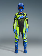 Motocross rider wearing complete racing gear, Alpinestars 2026 Techstar Nomur Pants and jersey in Yellow Fluo and Dark Navy, featuring blue accents and logos, paired with a blue helmet, gloves, and boots for a coordinated off-road racing look.