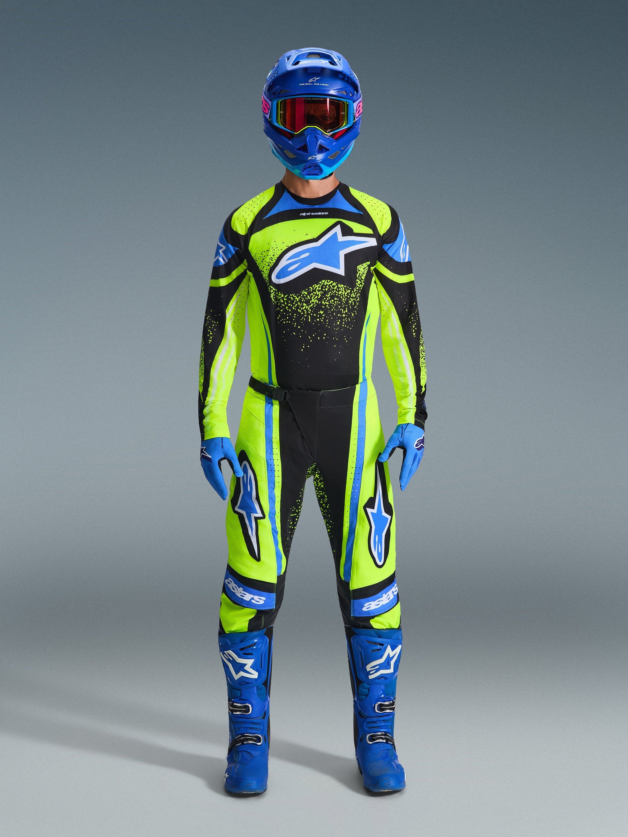 Motocross rider wearing complete racing gear, Alpinestars 2026 Techstar Nomur Pants and jersey in Yellow Fluo and Dark Navy, featuring blue accents and logos, paired with a blue helmet, gloves, and boots for a coordinated off-road racing look.