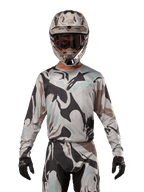 Alpinestars 2024 Racer Tactical Jersey, Motocross Jersey, Iron Camo Dust Gray camouflage pattern, rider wearing matching helmet and goggles with black gloves, technical gear for off-road racing