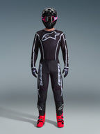 Alpinestars 2026 Fluid Apex Gear Set, Motocross Outfit, Black with Gray accents, jersey featuring large white Astars logo, matching pants with bold branding, black helmet with pink goggles, and bright red boots, complete off-road racing kit