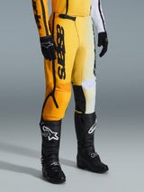 Alpinestars 2026 Fluid Apex Pants, Motocross Pants, Yellow and Black, worn with black boots and gloves, featuring bold 'astars' branding on the thigh, ergonomic design with reinforced panels, durable material for off-road riding