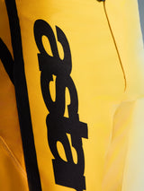 Close-up of Alpinestars 2026 Fluid Apex Pants, Motocross Pants, Yellow and Black, featuring a large vertical black logo, textured durable material, and ergonomic details for off-road performance