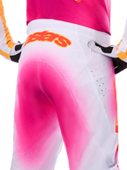 Alpinestars Limited Edition Supertech AFD MIG Pants, Motocross Pants, Pink Fluo and White with a spray-paint fade effect, large orange Alpinestars logo on the rear waistband, close-up view showing athletic fit and ventilation perforations.