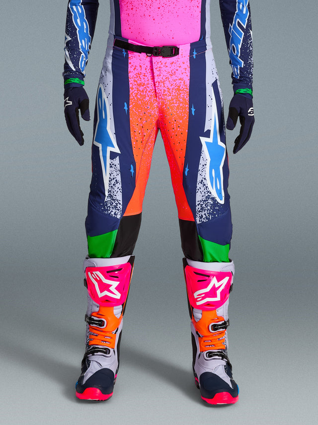 Alpinestars Limited Edition Supertech Records Pants, Motocross Pants, Multicolor featuring vibrant pink and orange splash graphics, navy panels with blue star logos, and green accents. Worn with matching jersey and grey, pink, and orange motocross boots.