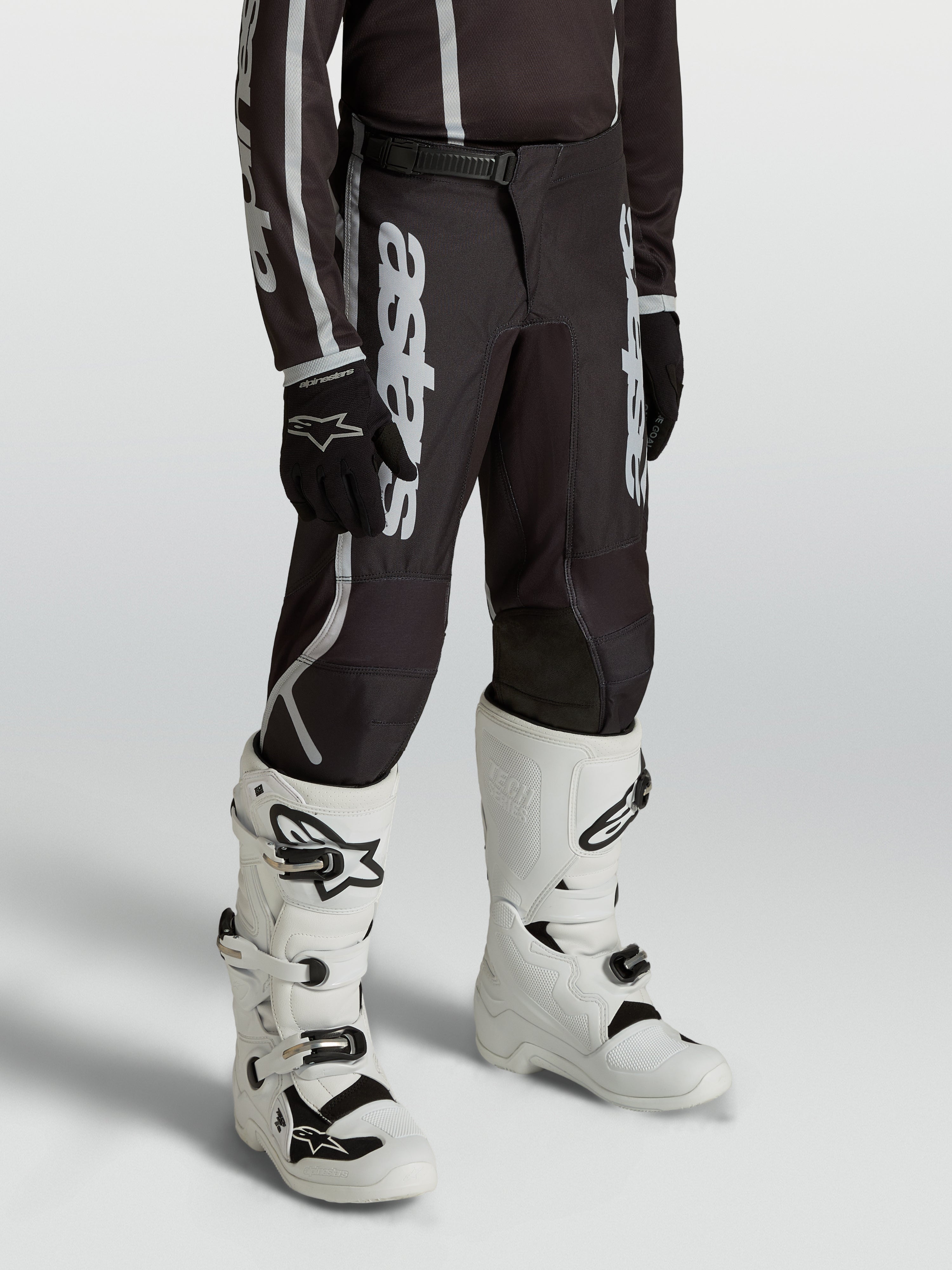 Alpinestars Youth Fluid Apex V2 Pants, black and silver motocross gear for young riders, featuring an ergonomic pre-curved fit.