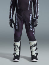 Alpinestars 2026 Youth Fluid Apex Pants, Motocross Pants, Black and Gray, featuring white 'Astars' vertical branding on thighs, worn with black gloves and white and black boots, durable material for youth off-road racing