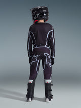 Rear view of a youth motocross rider wearing Alpinestars 2026 Youth Fluid Apex Pants in Black and Gray, matching long-sleeve jersey, black helmet, and black and white motocross boots, coordinated off-road racing gear.