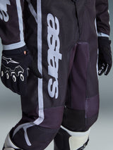 Alpinestars 2026 Youth Fluid Apex Pants, Motocross Pants, Black and Gray, close-up view showing white 'astars' branding on the leg, worn with matching black and white gloves and boots, sporty design for youth off-road racing