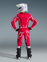 Alpinestars 2026 Youth Fluid Apex Pants, Motocross Pants, Red and White, rear view showing matching jersey, white helmet, and black and white boots, featuring bold white geometric patterns and large Alpinestars logo on the back, complete youth racing gear set.