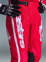 Alpinestars 2026 Youth Fluid Apex Pants, Motocross Pants, Red and White, featuring black ratchet waist closure and bold white Alpinestars branding on the thigh, worn with black and white gloves, durable polyfabric for off-road racing