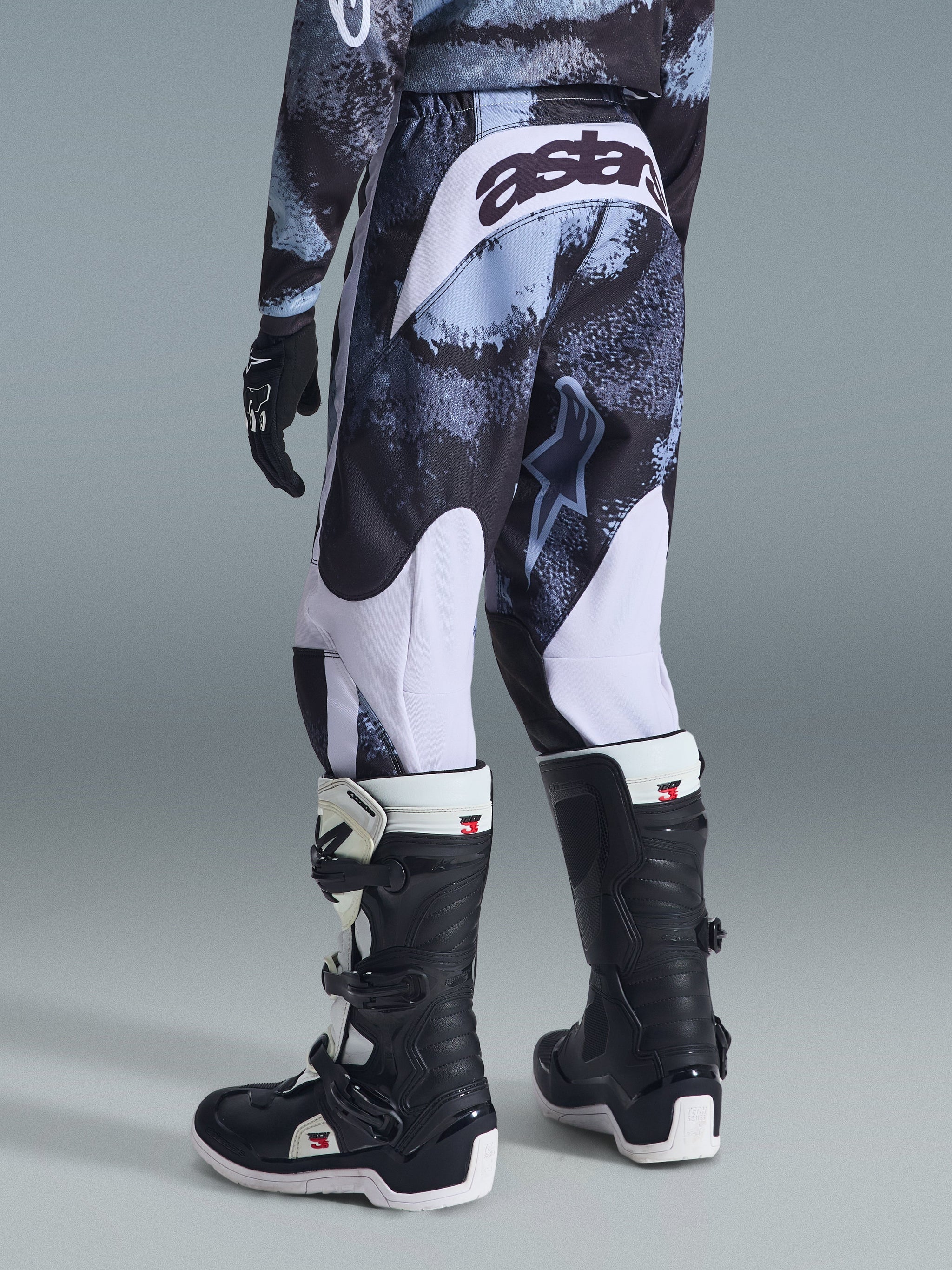 Alpinestars 2026 Youth Fluid Lahnd Pants, Motocross Pants, Iron Camo with white accents, rear view showing 'astars' branding on the seat, worn with matching camo jersey and black and white Tech 3 motocross boots.