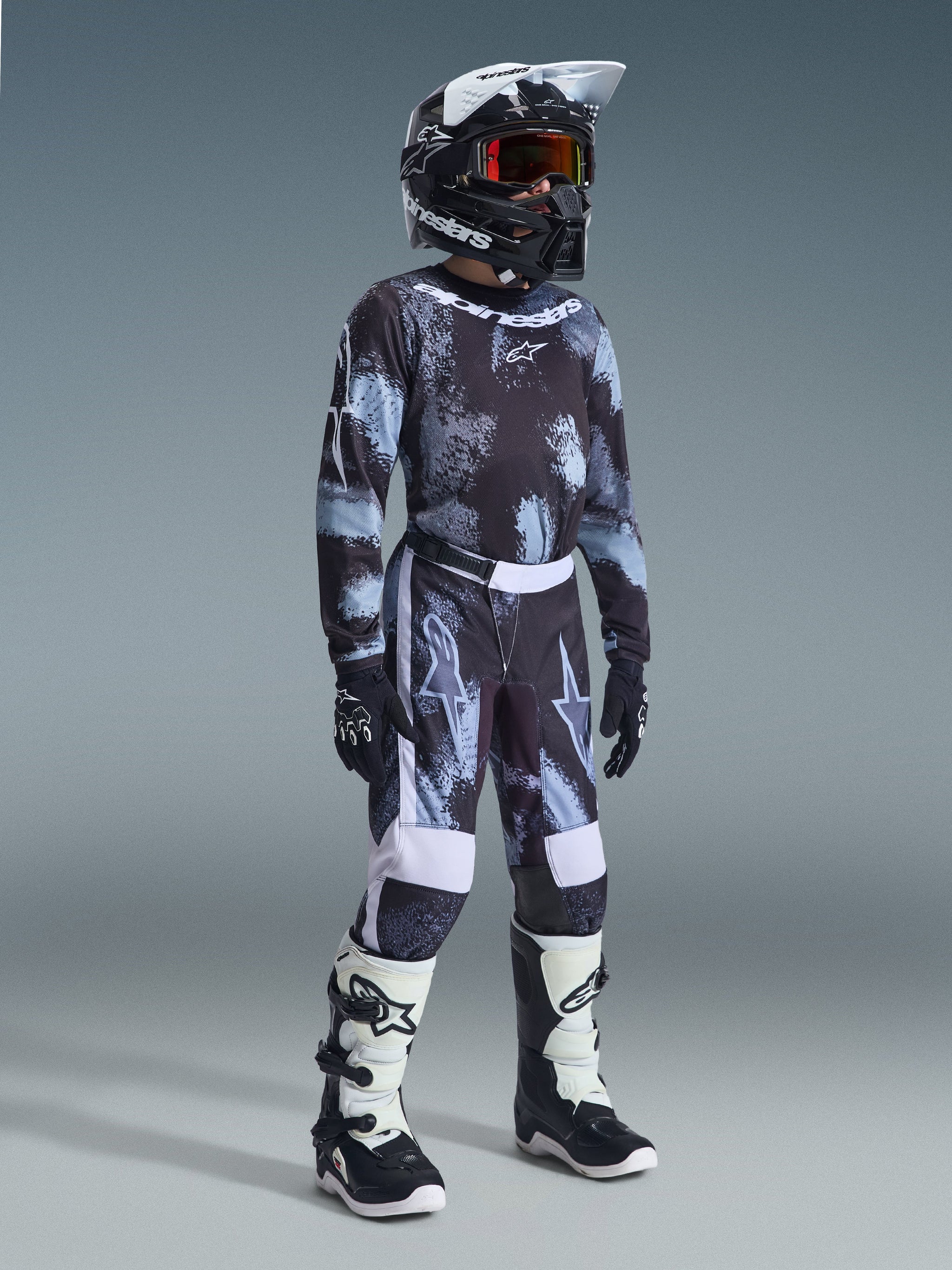 Alpinestars 2026 Youth Fluid Lahnd Pants, Motocross Pants, Iron Camo, complete youth racing outfit with matching jersey, black helmet, and white and black boots, high-performance off-road gear for young riders