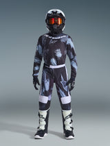 Alpinestars 2026 Youth Fluid Lahnd Pants, Motocross Pants, Iron Camo, worn by a youth rider with matching camo jersey, black helmet with orange goggles, and white and black boots, featuring a coordinated design with bold logos and reinforced panels for off-road racing.