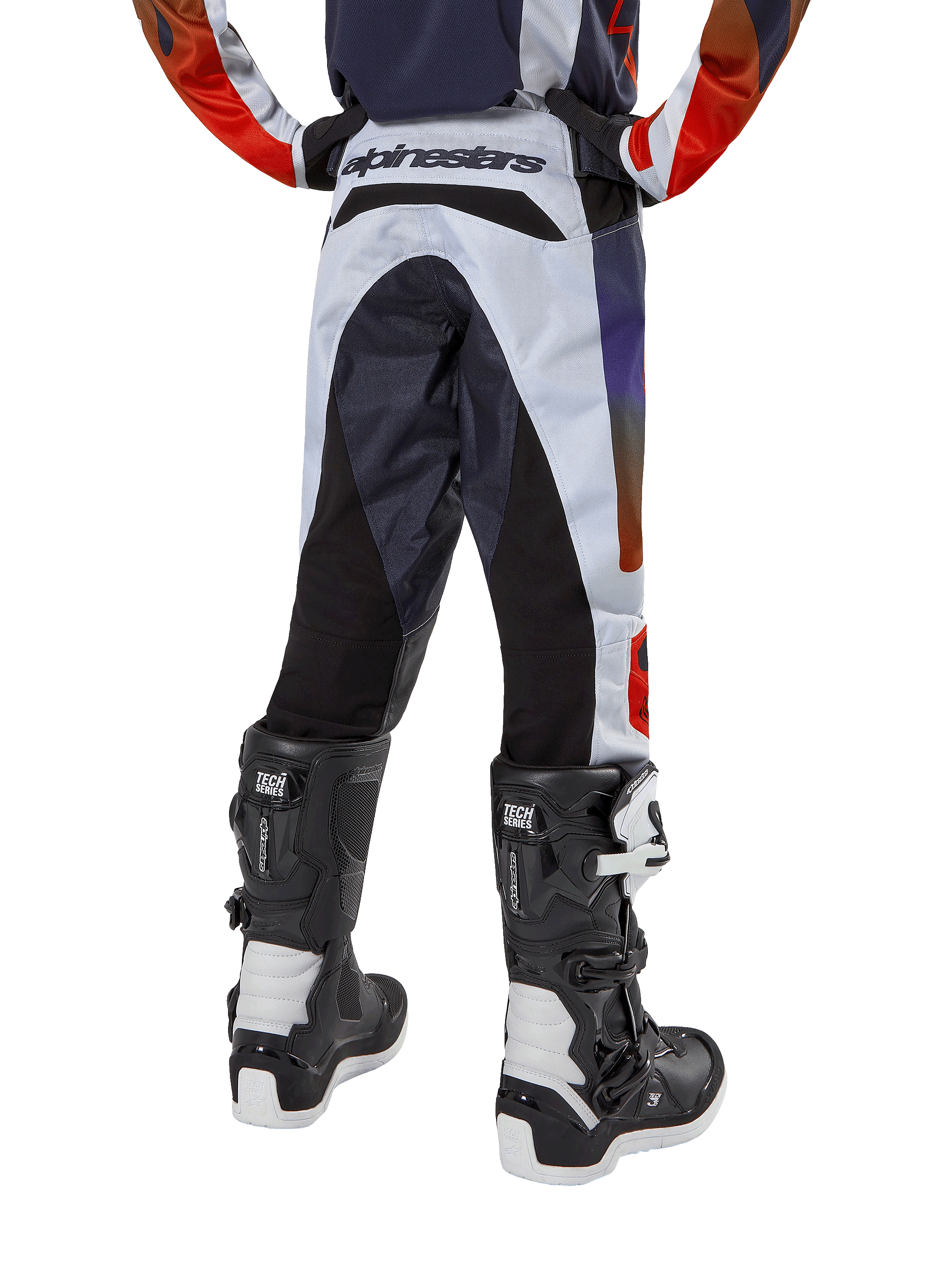Alpinestars Youth 2024 Racer Hoen Pants, Motocross Pants, Light Gray with Hot Orange and Black accents, rear view featuring black panels on the seat and legs, bold branding on the back waist, worn with black and white motocross boots for off-road racing