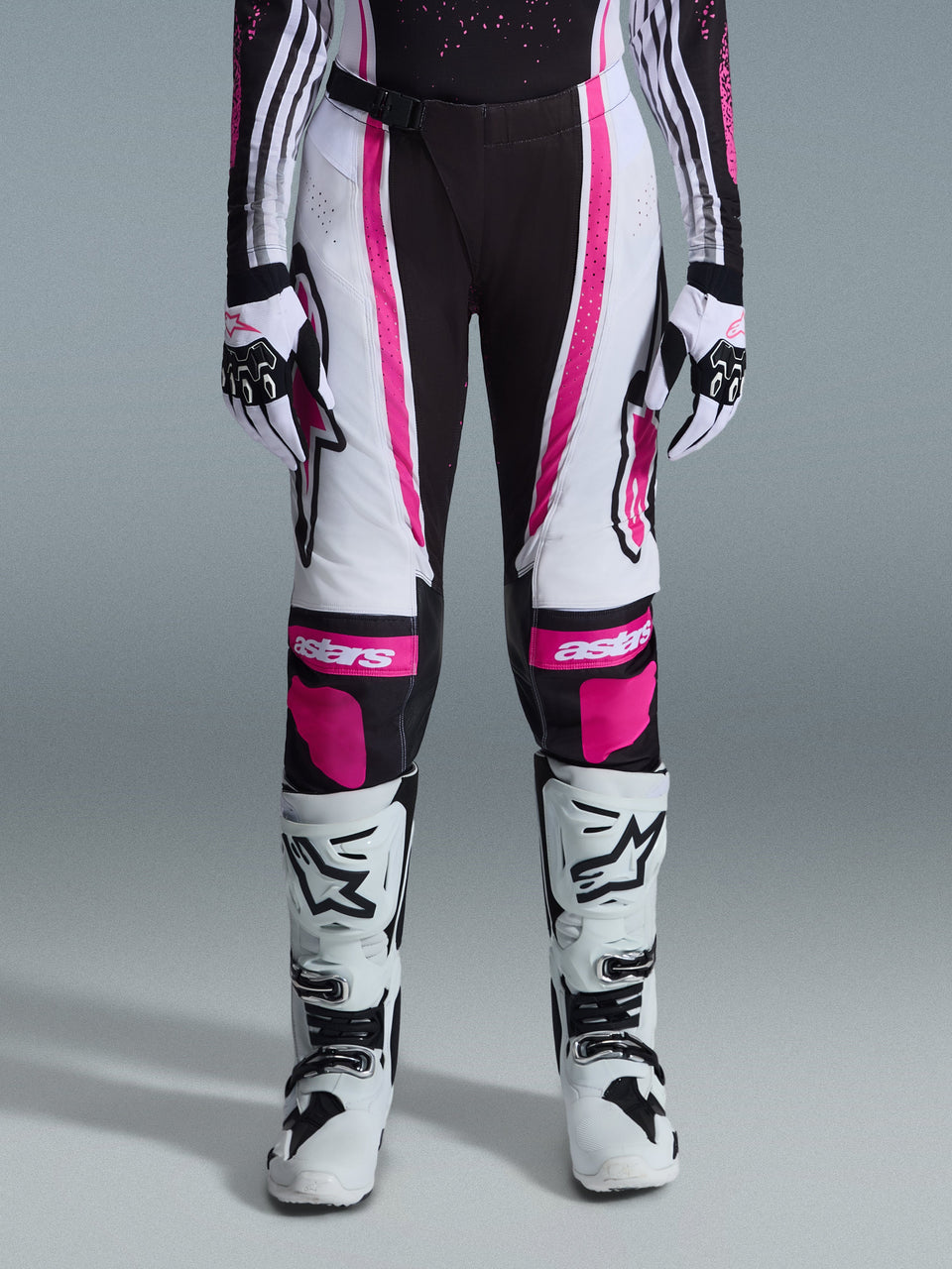 Alpinestars 2026 Woman Stella Techstar Nomur Pants, Motocross Pants, Black White and Fuchsia, worn with matching racing jersey, gloves, and white motocross boots, featuring bold pink graphics and astars logos on the knees, designed for high-level off-road competition.