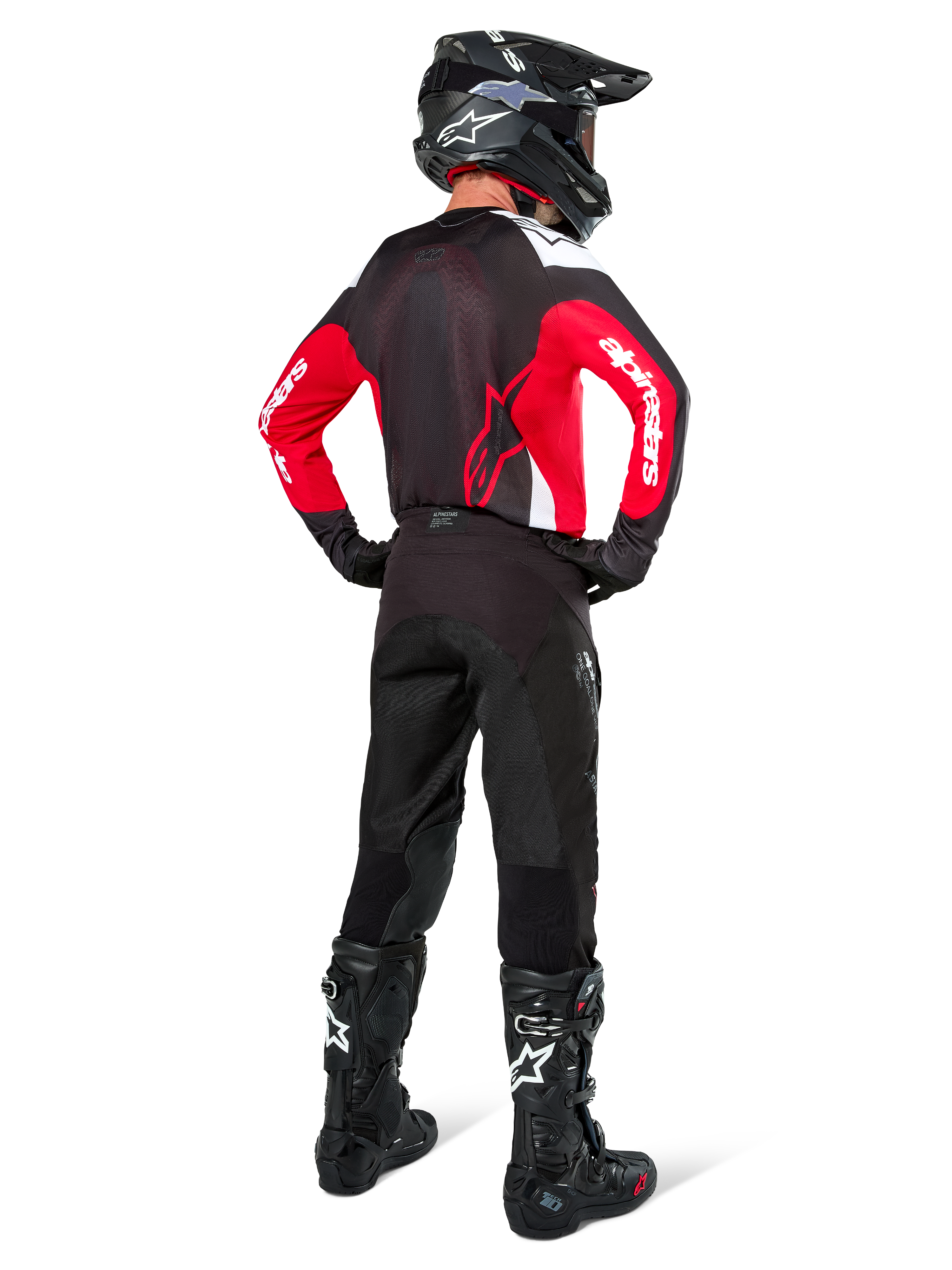 Motocross rider from behind wearing the Alpinestars Pro-Dura Jersey in Black, Bright Red, and White, paired with black motocross pants, helmet, and boots, showing the rear design and sleeve logos, coordinated off-road racing gear.