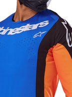 Alpinestars 2025 Techstar Melt Jersey, Motocross Jersey, Blue and Orange with black panels, featuring white Alpinestars branding and visible laser-cut perforations on the chest, worn by a rider in a black helmet