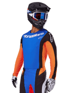 Alpinestars 2025 Techstar Melt Gear Set, Motocross rider wearing a blue jersey with orange sleeves and black side panels, matching blue and black pants, black helmet with blue goggles, white and black gloves, athletic race-fit motocross apparel