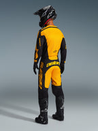 Motocross rider from behind wearing the Alpinestars 2026 Racer Riway Gear Set, Yellow and Black jersey and matching pants, black helmet, black gloves, and black boots with white accents, coordinated outfit for professional off-road racing.
