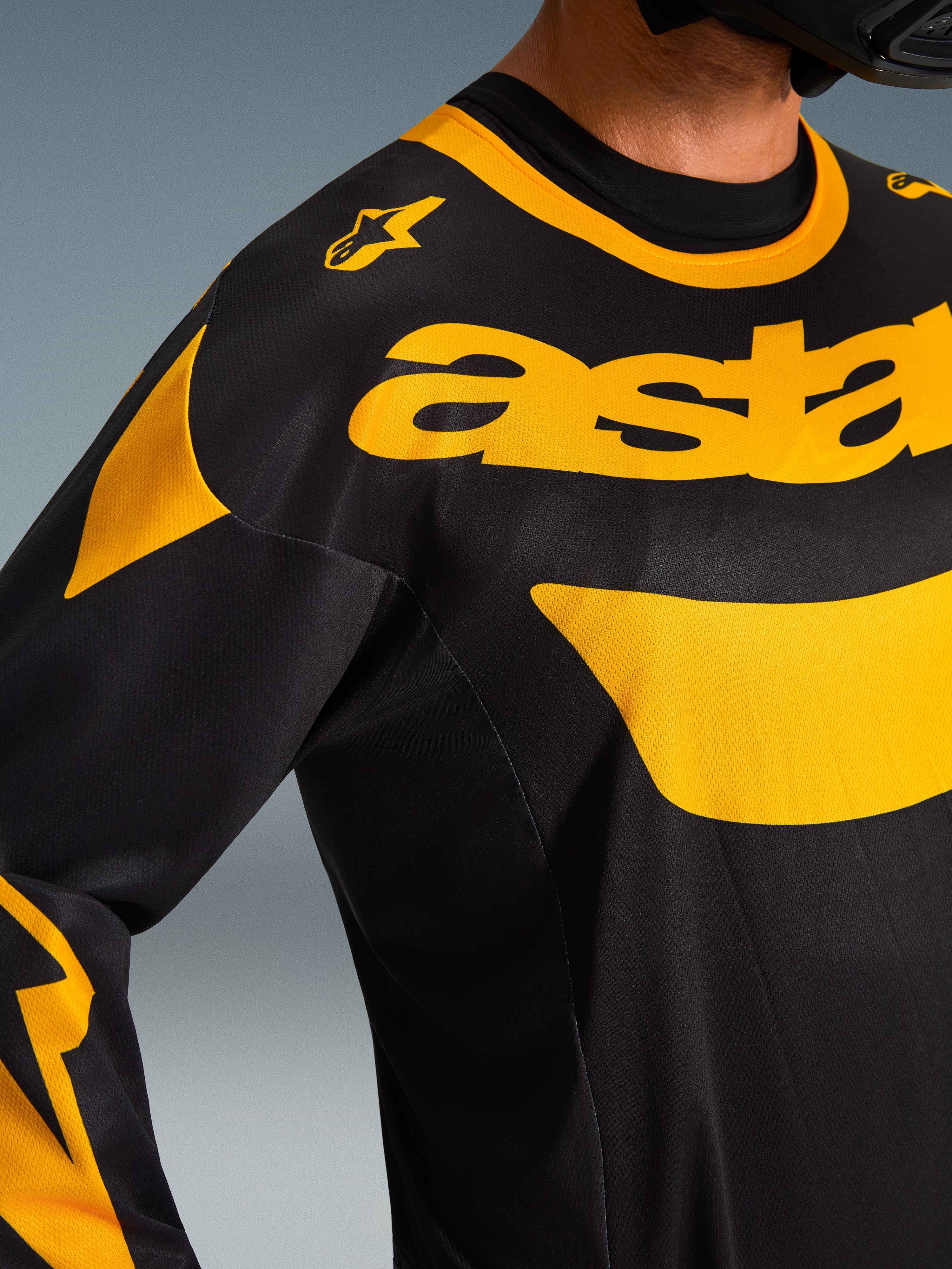 Close-up of Alpinestars 2026 Racer Riway Jersey, Black and Yellow, featuring bold yellow branding across the chest, technical mesh fabric construction for ventilation, performance motocross apparel