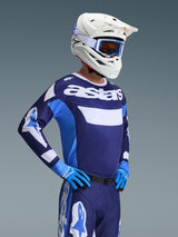 Motocross rider wearing the Alpinestars 2026 Racer Riway Jersey in UCLA Blue White, featuring 'astars' branding on the chest, paired with matching blue motocross pants, white helmet with goggles, and blue gloves, high-performance off-road racing gear