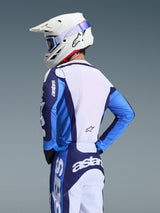 Motocross rider wearing the 2026 Racer Riway Jersey in UCLA Blue and White, back view showing the extended rear cut and athletic fit, paired with matching blue and white motocross pants and a white helmet, coordinated gear set for off-road racing.