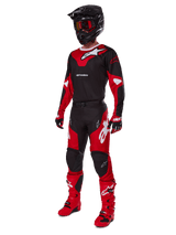 Motocross rider wearing complete racing gear featuring the Alpinestars 2025 Racer Veil Jersey in Black and Bright Red, matching pants, red boots, black helmet with red goggles, and red and black gloves, coordinated performance look for off-road racing