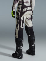 Alpinestars 2026 Racer Lahnd Pants, Motocross Pants, Sand Camo and Gray, rear view featuring bold white branding on the seat and legs, paired with black motocross boots and yellow gloves, professional off-road racing gear