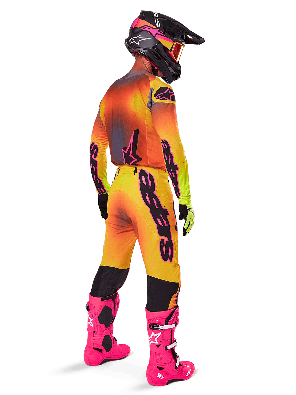 Motocross rider from behind wearing the Alpinestars 2025 Supertech Lipan Gear Set, yellow and orange gradient jersey with pink accents, matching pants, bright pink boots, and a black helmet with pink and yellow graphics, coordinated outfit for professional racing