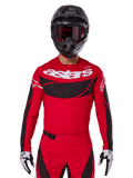 Alpinestars 2025 Techstar Dreem Jersey, Motocross Gear, Bright Red and Black, featuring a white 'astars' logo and black ventilated chest panel, worn with matching pants, black helmet, and white and black gloves, designed for professional off-road racing